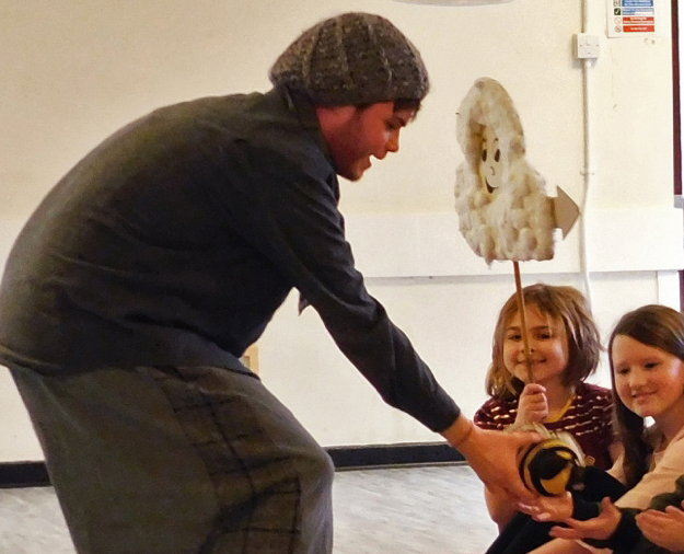 A photo of a white man puppetting a bee while a child holds a cloud