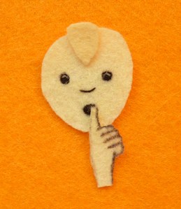 A felt image of a person shushing with their finger on their lips