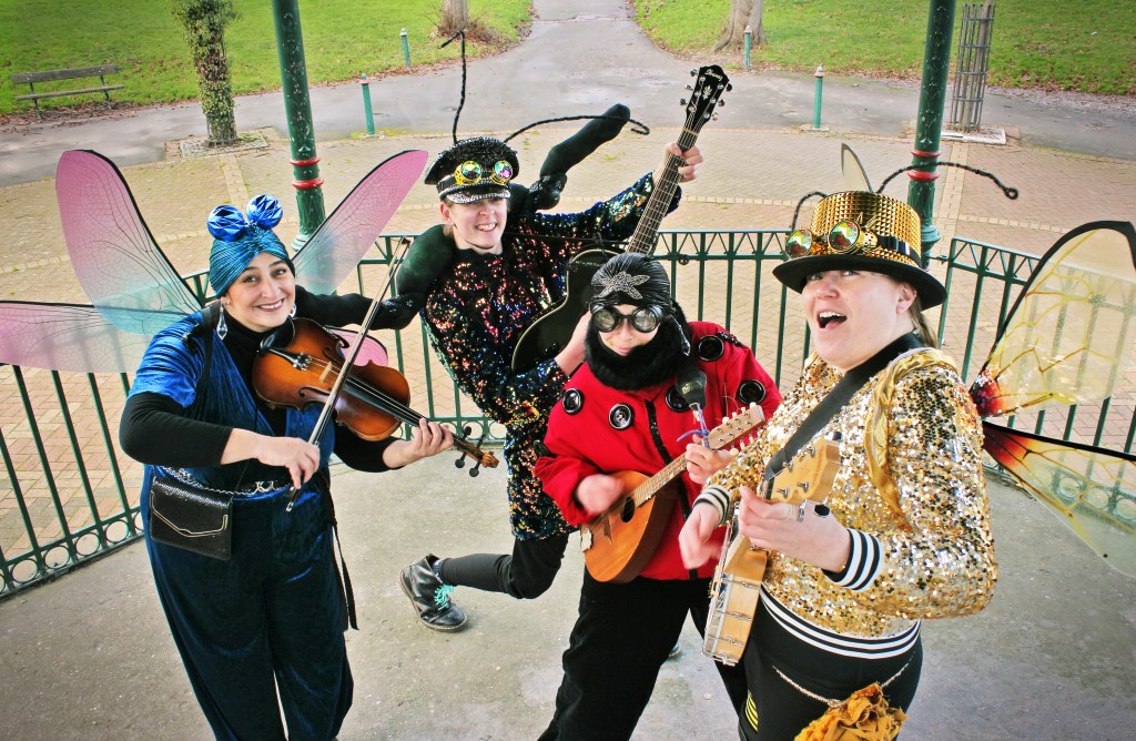 A photo of four musicians dressed in insect costumes